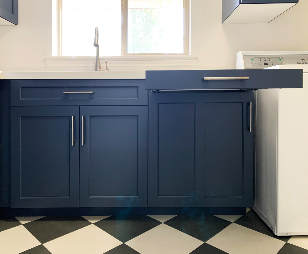 Inspiration for a large transitional l-shaped utility room in Salt Lake City with an undermount sink, shaker cabinets, blue cabinets, quartz benchtops, white splashback, engineered quartz splashback, white walls, ceramic floors, a side-by-side washer and dryer, multi-coloured floor and white benchtop.