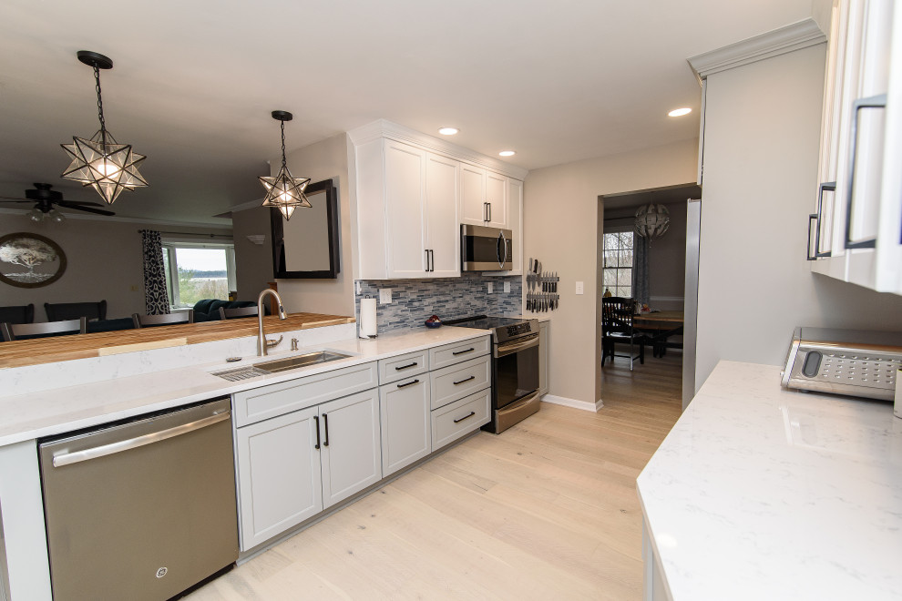 Mid-sized transitional u-shaped enclosed kitchen photo in Baltimore with an undermount sink, shaker cabinets, white cabinets, quartz countertops, blue backsplash, subway tile backsplash, stainless steel appliances, a peninsula and white countertops