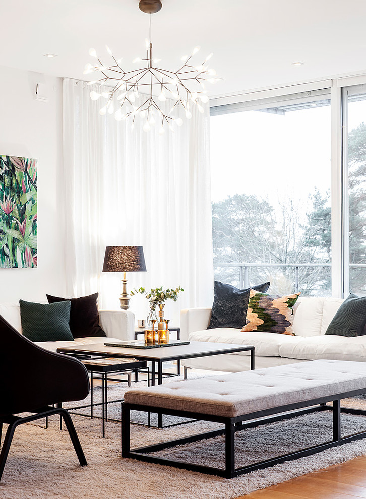 This is an example of a large contemporary formal open concept living room in Gothenburg with white walls, medium hardwood floors, no fireplace, no tv and brown floor.
