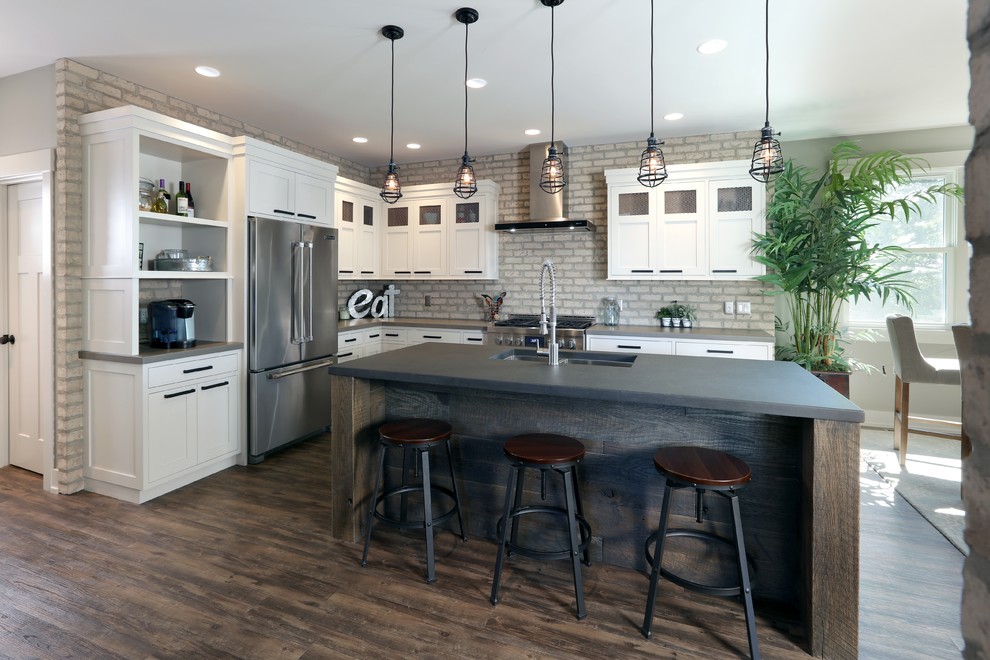This is an example of an industrial l-shaped kitchen in Grand Rapids with a double-bowl sink, recessed-panel cabinets, white cabinets, concrete benchtops, stainless steel appliances, dark hardwood floors and with island.
