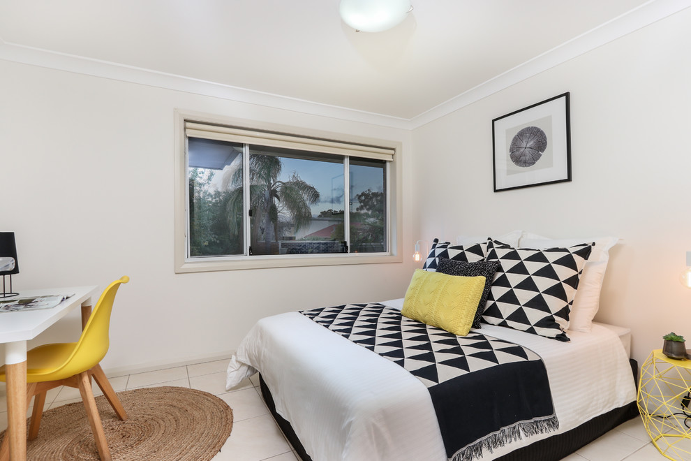 Beach style guest bedroom in Sydney with beige walls and beige floor.