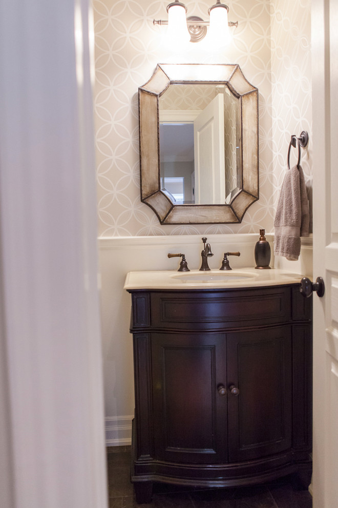 This is an example of a small transitional powder room in Toronto with an undermount sink, recessed-panel cabinets, dark wood cabinets, marble benchtops, a two-piece toilet and beige walls.