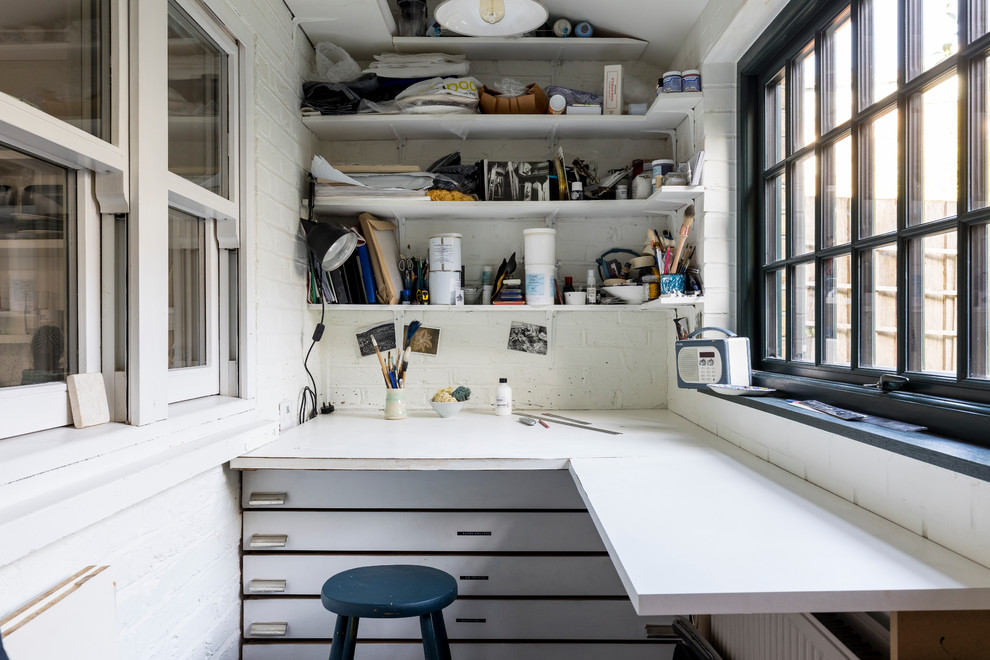 This is an example of a small industrial craft room in London with white walls, limestone floors, no fireplace, a built-in desk and grey floor.