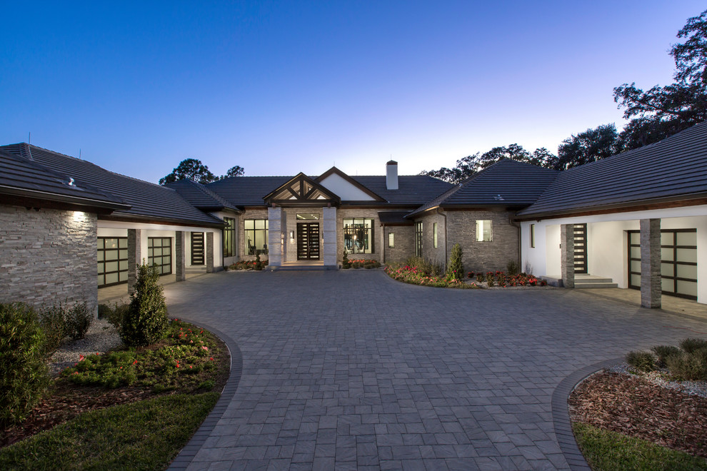 Expansive transitional grey house exterior in Orlando with mixed siding, a hip roof and a shingle roof.