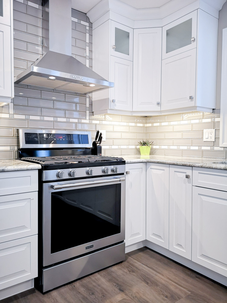 Enclosed kitchen - mid-sized transitional u-shaped light wood floor and brown floor enclosed kitchen idea in Toronto with an undermount sink, raised-panel cabinets, white cabinets, granite countertops, beige backsplash, glass tile backsplash, stainless steel appliances, a peninsula and gray countertops