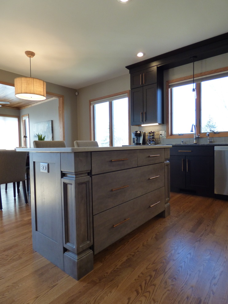 Example of a large transitional l-shaped medium tone wood floor eat-in kitchen design in Cedar Rapids with an undermount sink, shaker cabinets, dark wood cabinets, quartz countertops, gray backsplash, porcelain backsplash, stainless steel appliances and an island