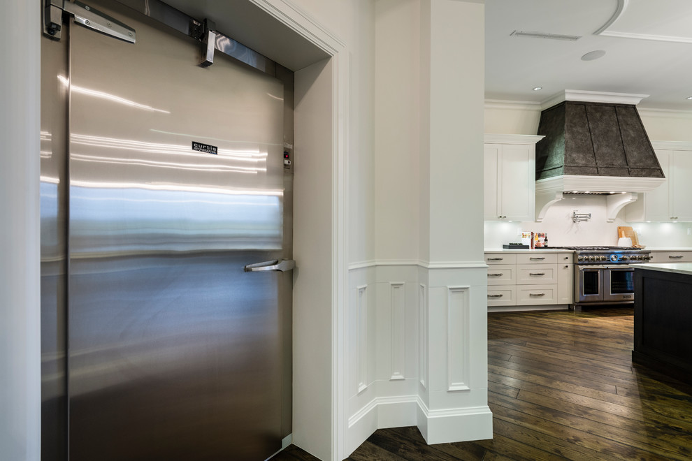 Inspiration for a huge rustic u-shaped medium tone wood floor and brown floor open concept kitchen remodel in Vancouver with an undermount sink, shaker cabinets, white cabinets, solid surface countertops, white backsplash, stone slab backsplash, stainless steel appliances, an island and white countertops