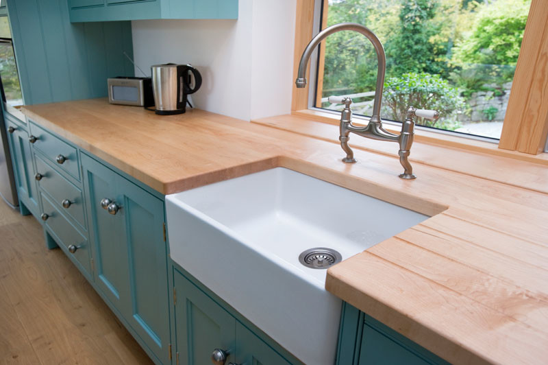 Photo of a large beach style eat-in kitchen in Cornwall with an undermount sink, blue cabinets, wood benchtops, stainless steel appliances, medium hardwood floors and with island.