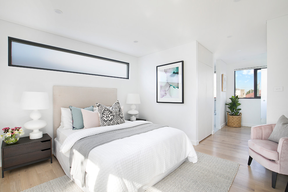 Photo of a contemporary guest bedroom in Sydney with white walls, light hardwood floors, no fireplace and brown floor.