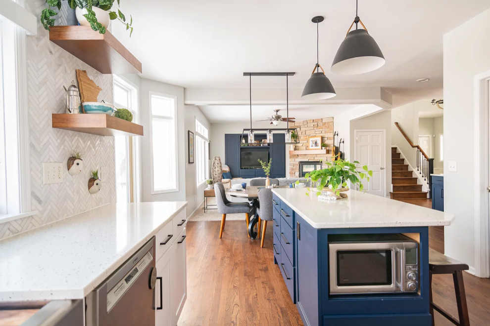 This is an example of a large rural u-shaped kitchen/diner in Minneapolis with a single-bowl sink, shaker cabinets, white cabinets, engineered stone countertops, white splashback, marble splashback, stainless steel appliances, medium hardwood flooring, an island, brown floors and white worktops.