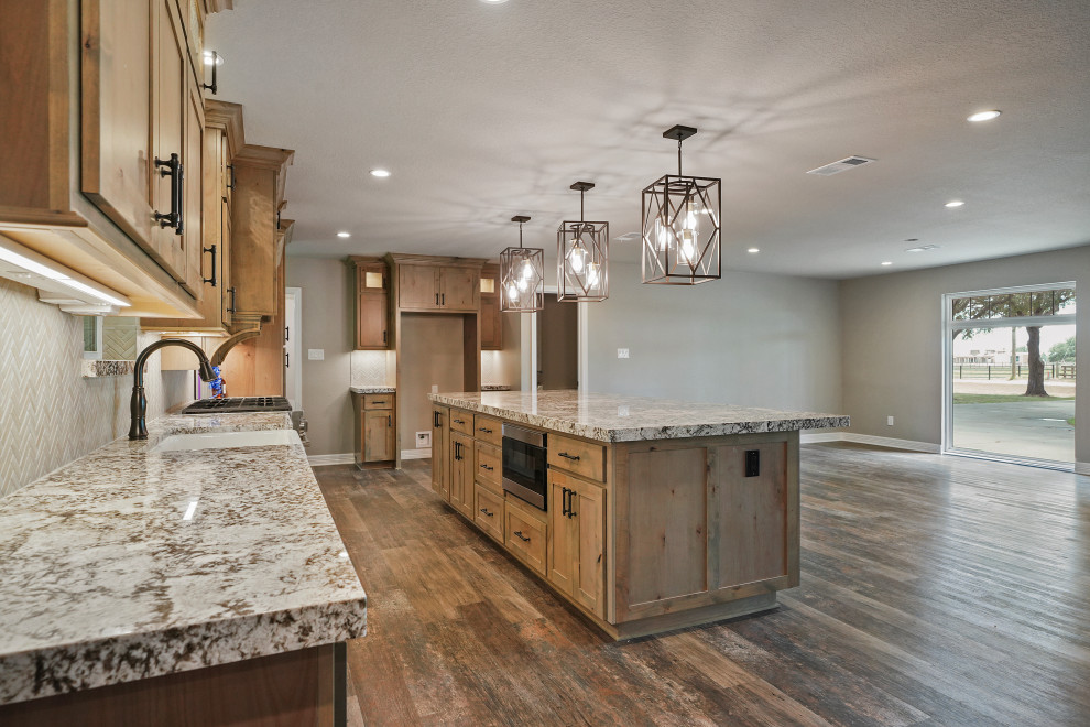 Inspiration for a large craftsman dark wood floor and brown floor eat-in kitchen remodel in Houston with a farmhouse sink, shaker cabinets, distressed cabinets, granite countertops, beige backsplash, porcelain backsplash, stainless steel appliances, an island and brown countertops