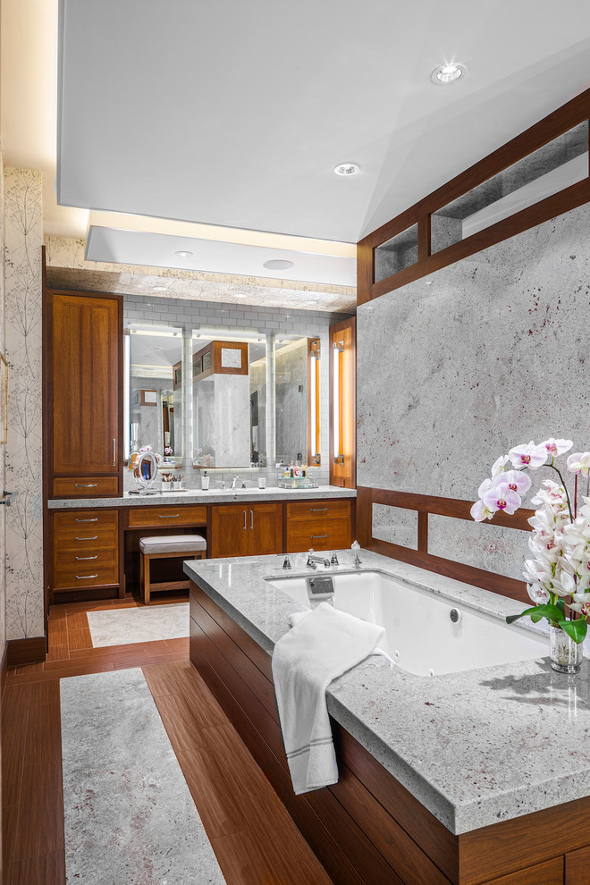 This is an example of a large contemporary master bathroom in Boston with recessed-panel cabinets, medium wood cabinets, granite benchtops, an undermount tub, an undermount sink, grey walls, medium hardwood floors and brown floor.