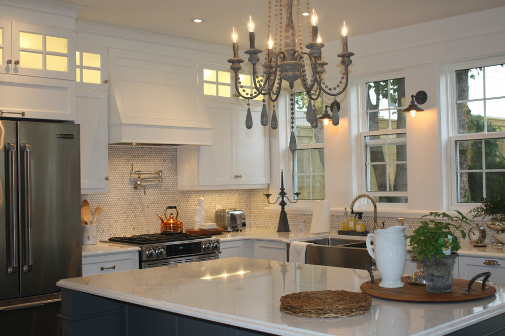 Example of a mid-sized transitional l-shaped kitchen design with a double-bowl sink, shaker cabinets, white cabinets, white backsplash, mosaic tile backsplash, stainless steel appliances and an island
