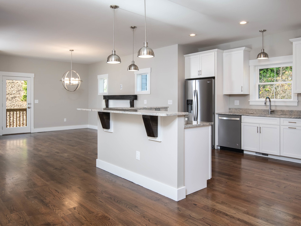 Design ideas for a mid-sized transitional l-shaped eat-in kitchen in Other with a single-bowl sink, shaker cabinets, white cabinets, granite benchtops, stainless steel appliances, dark hardwood floors, with island, brown floor and grey benchtop.
