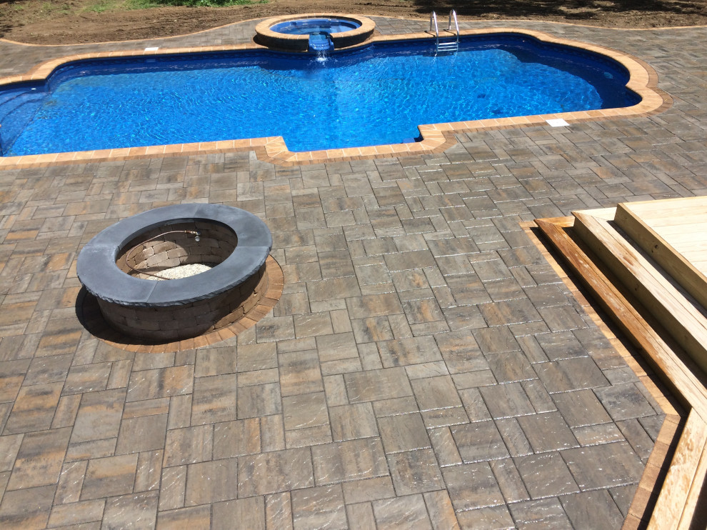 Example of a large transitional backyard concrete paver and custom-shaped hot tub design
