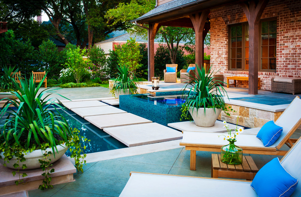 Large modern backyard custom-shaped pool in Dallas with natural stone pavers and a hot tub.