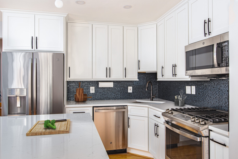Inspiration for a small contemporary l-shaped eat-in kitchen in DC Metro with an undermount sink, shaker cabinets, white cabinets, quartz benchtops, blue splashback, mosaic tile splashback, stainless steel appliances, light hardwood floors, with island, brown floor and white benchtop.