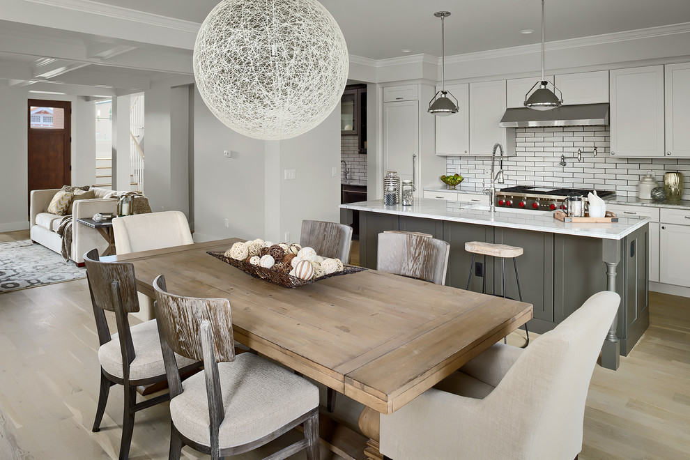 Inspiration for a mid-sized contemporary single-wall eat-in kitchen in Denver with an undermount sink, flat-panel cabinets, marble benchtops, white splashback, ceramic splashback, panelled appliances, light hardwood floors, with island, beige floor, white benchtop and white cabinets.
