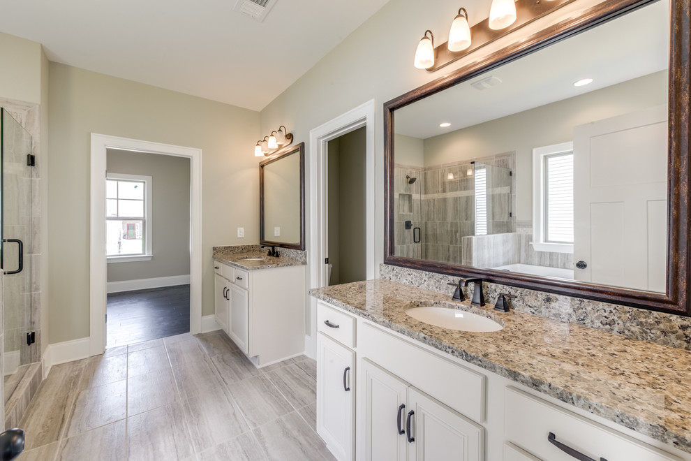 Photo of a mid-sized transitional master wet room bathroom in Other with recessed-panel cabinets, white cabinets, a drop-in tub, beige tile, porcelain tile, grey walls, porcelain floors, an undermount sink, granite benchtops, grey floor and a hinged shower door.