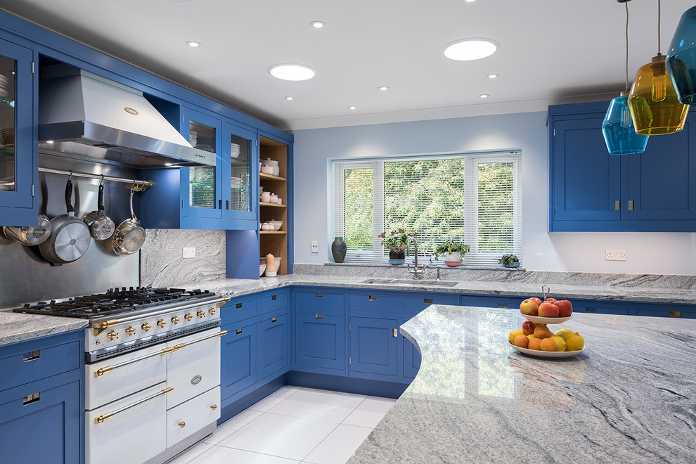 Design ideas for a mid-sized contemporary l-shaped open plan kitchen in Hampshire with a drop-in sink, shaker cabinets, blue cabinets, granite benchtops, grey splashback, marble splashback, white appliances, ceramic floors, with island, white floor and grey benchtop.