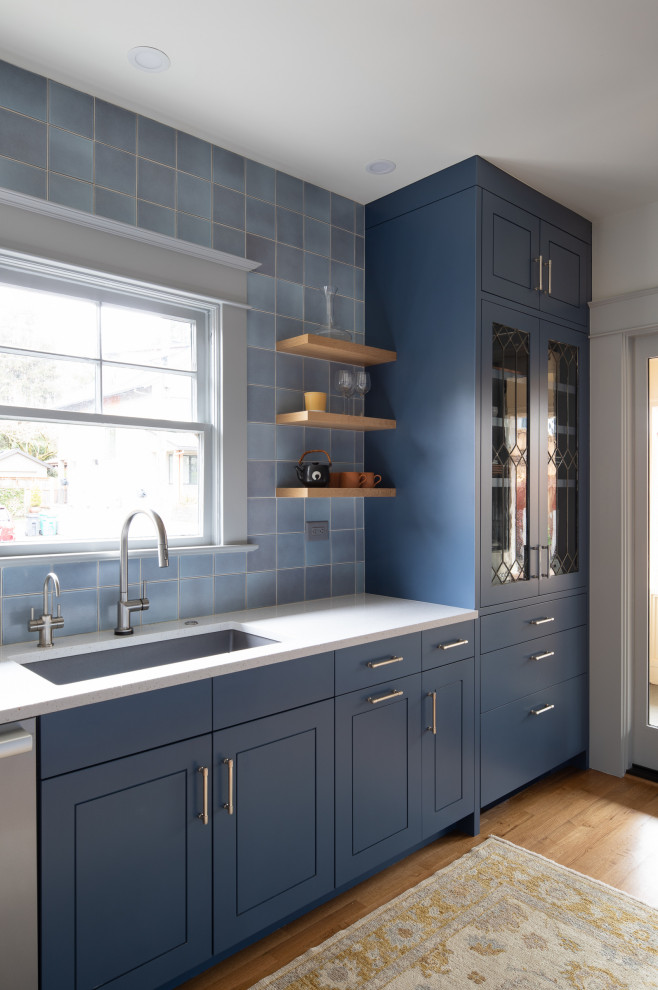 Inspiration for an arts and crafts galley kitchen in Portland with blue cabinets, multi-coloured splashback, subway tile splashback, stainless steel appliances and white benchtop.