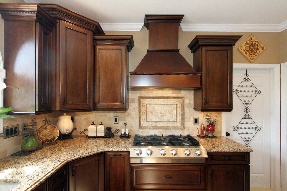 This is an example of a mid-sized traditional eat-in kitchen in New York with an undermount sink, recessed-panel cabinets, dark wood cabinets, granite benchtops, beige splashback, stone tile splashback, black appliances, porcelain floors and with island.