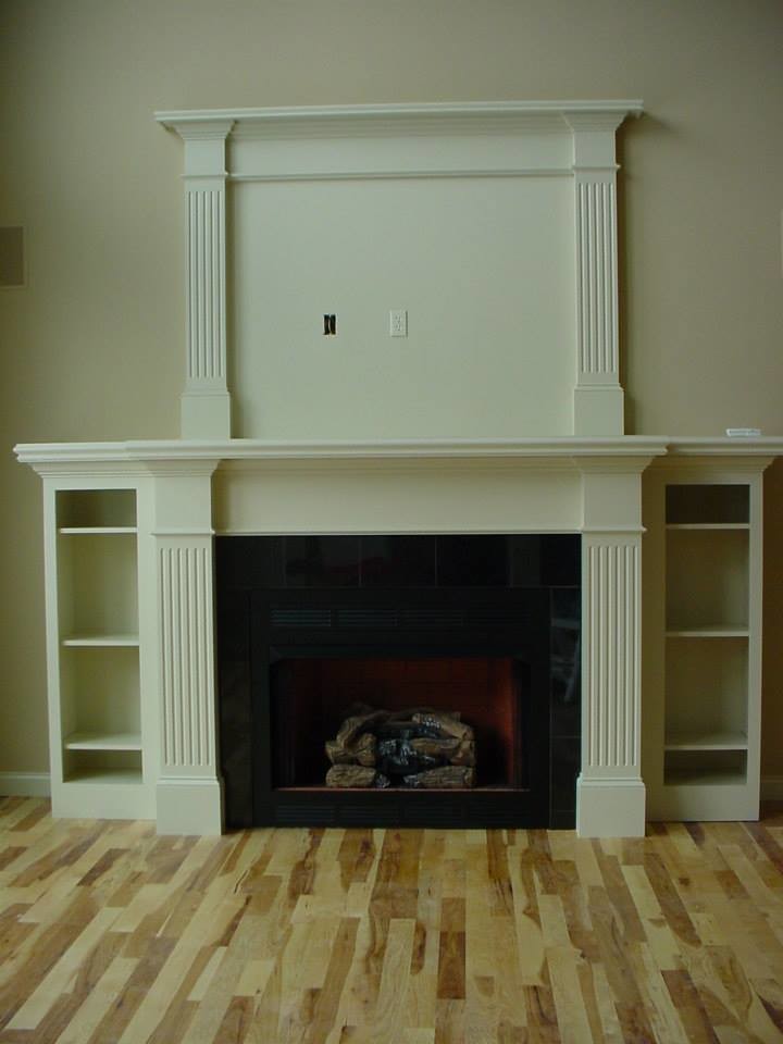 Medium tone wood floor living room photo with beige walls, a standard fireplace, a wood fireplace surround and no tv