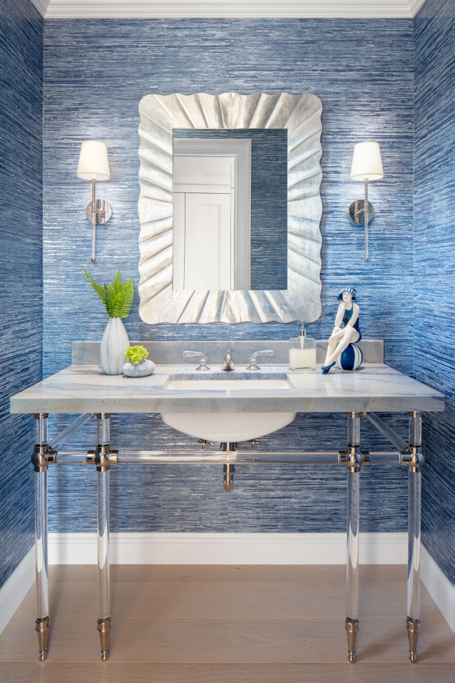 Example of a transitional light wood floor, beige floor and wallpaper powder room design in Boston with open cabinets, gray cabinets, blue walls, an undermount sink, marble countertops, gray countertops and a freestanding vanity