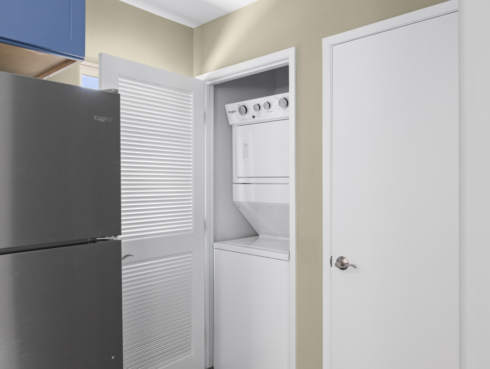 Diseño de armario lavadero contemporáneo pequeño con paredes beige, suelo de madera en tonos medios, lavadora y secadora integrada y suelo gris
