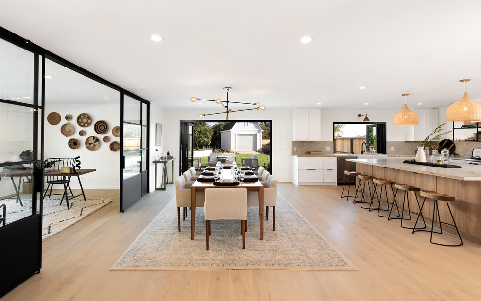 Photo of a large beach style open plan dining in Santa Barbara with white walls and light hardwood floors.