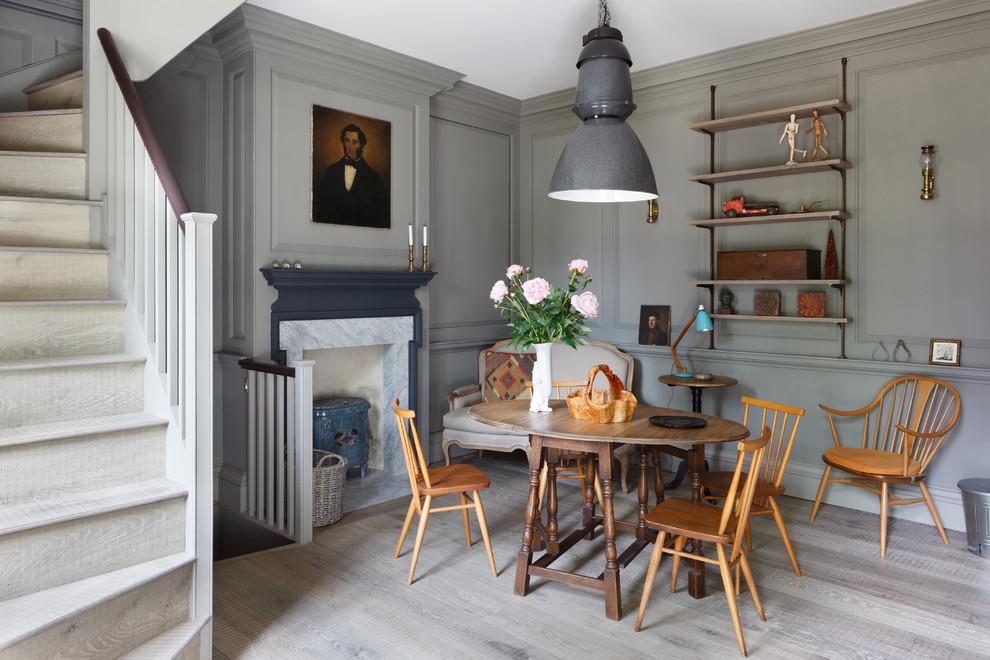 Small traditional dining room in London with medium hardwood floors, a wood stove, a stone fireplace surround and grey walls.