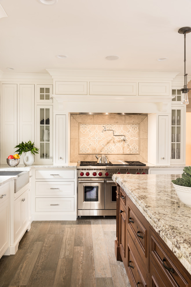 Mid-sized transitional l-shaped open plan kitchen in Boston with a farmhouse sink, white cabinets, granite benchtops, brown splashback, panelled appliances, medium hardwood floors, with island, brown floor, brown benchtop, porcelain splashback and beaded inset cabinets.