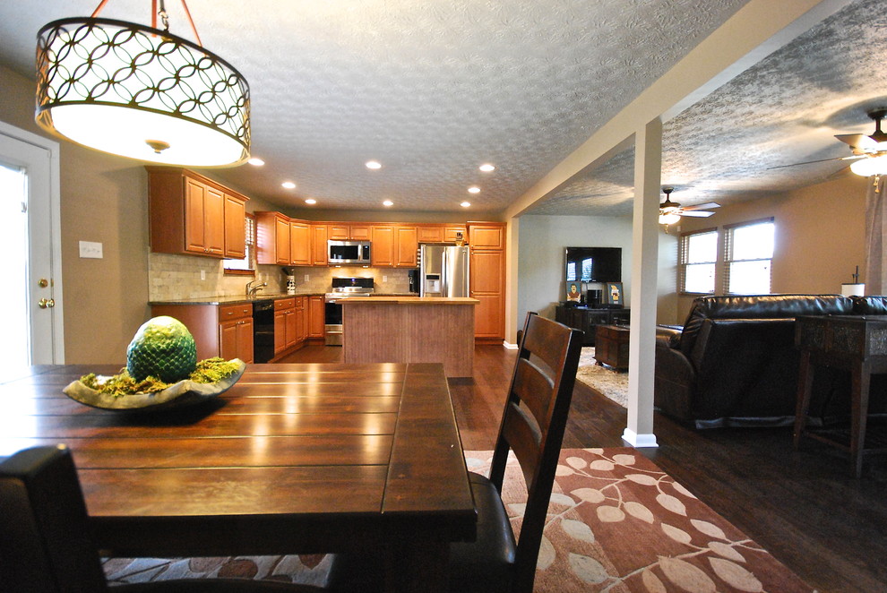 Open concept kitchen - mid-sized transitional l-shaped dark wood floor and brown floor open concept kitchen idea with an undermount sink, raised-panel cabinets, granite countertops, beige backsplash, stainless steel appliances, an island, medium tone wood cabinets and stone tile backsplash