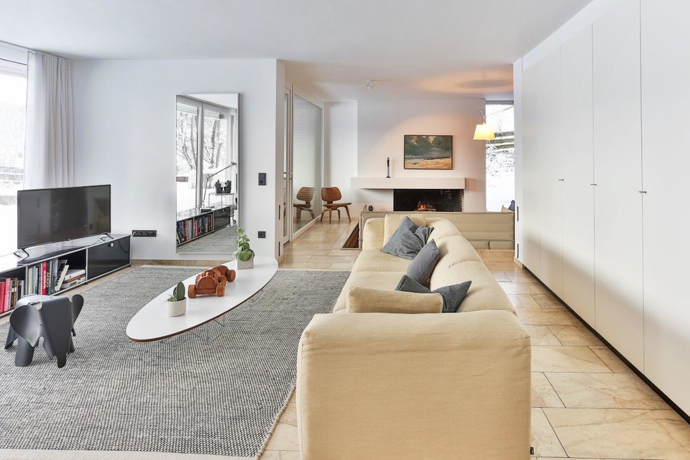 This is an example of a modern open concept living room in Cologne with white walls, marble floors, a wood stove, a brick fireplace surround, a freestanding tv, beige floor, wallpaper and wallpaper.