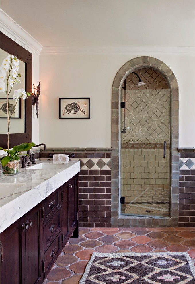 Design ideas for a mediterranean master bathroom in Los Angeles with an undermount sink, dark wood cabinets, marble benchtops, an alcove shower, multi-coloured tile, beige walls, terra-cotta floors and recessed-panel cabinets.