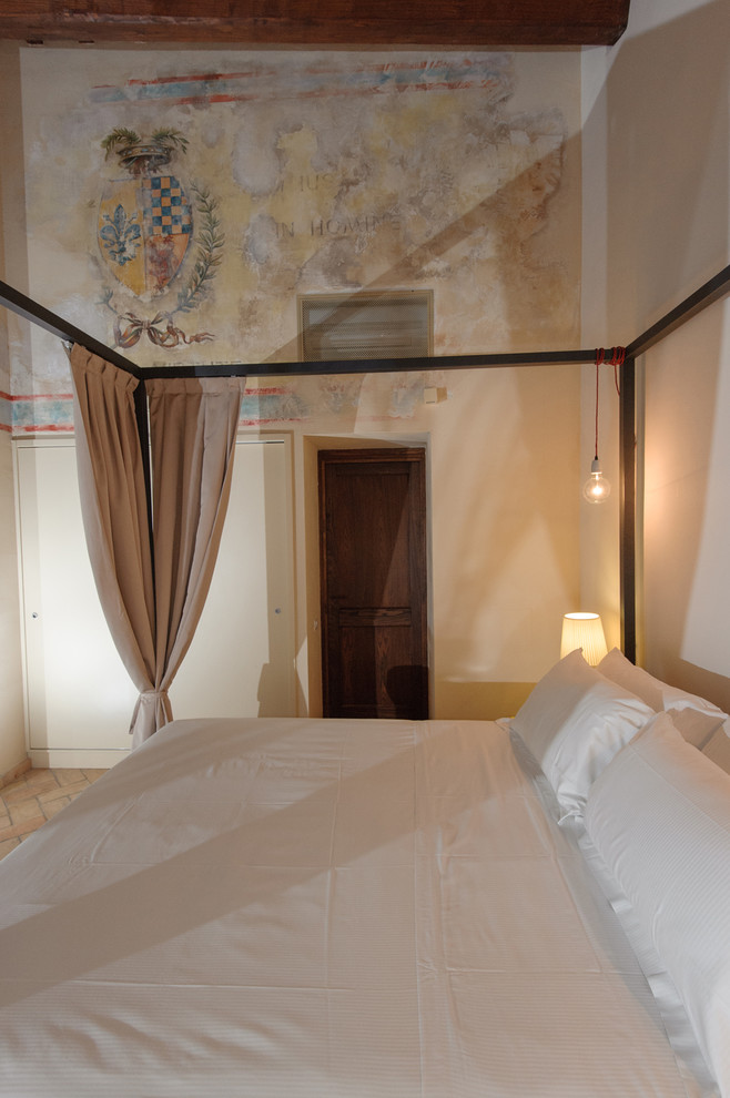 Design ideas for a mid-sized traditional bedroom in Rome with beige walls, brick floors and beige floor.