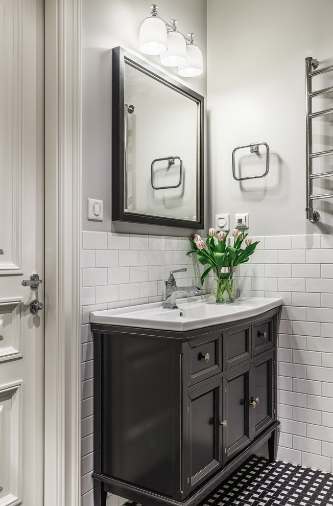 This is an example of a small traditional bathroom in Other with recessed-panel cabinets, black cabinets, white tile, ceramic tile, grey walls, porcelain floors, an integrated sink and multi-coloured floor.