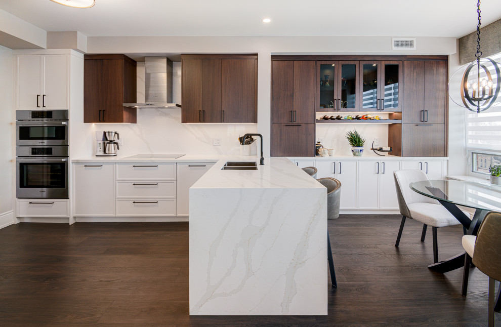 Mid-sized transitional u-shaped laminate floor and brown floor eat-in kitchen photo in Toronto with an undermount sink, shaker cabinets, medium tone wood cabinets, quartzite countertops, white backsplash, stone slab backsplash, stainless steel appliances, a peninsula and white countertops