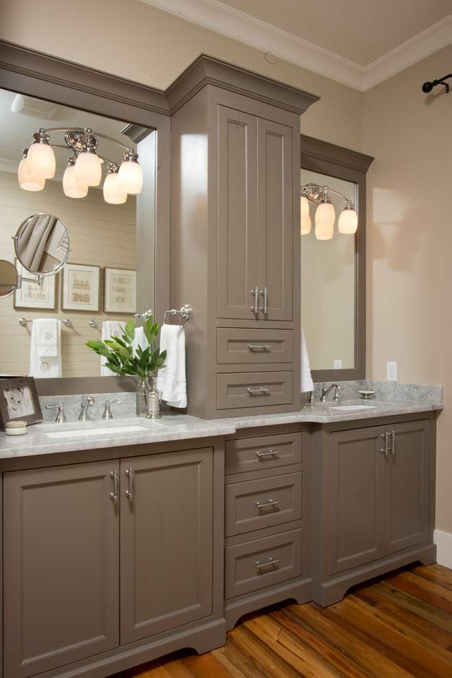 Photo of a mid-sized country bathroom in Charleston with an undermount sink, recessed-panel cabinets, grey walls, medium hardwood floors, marble benchtops and brown cabinets.