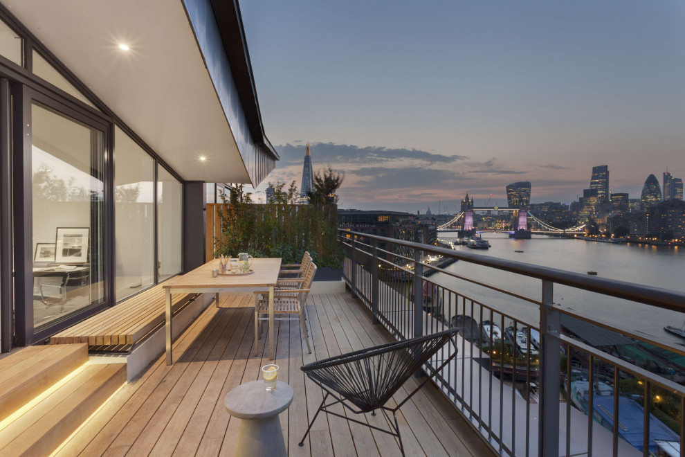 This is an example of a mid-sized contemporary first floor deck in London with with dock, a roof extension and metal railing.