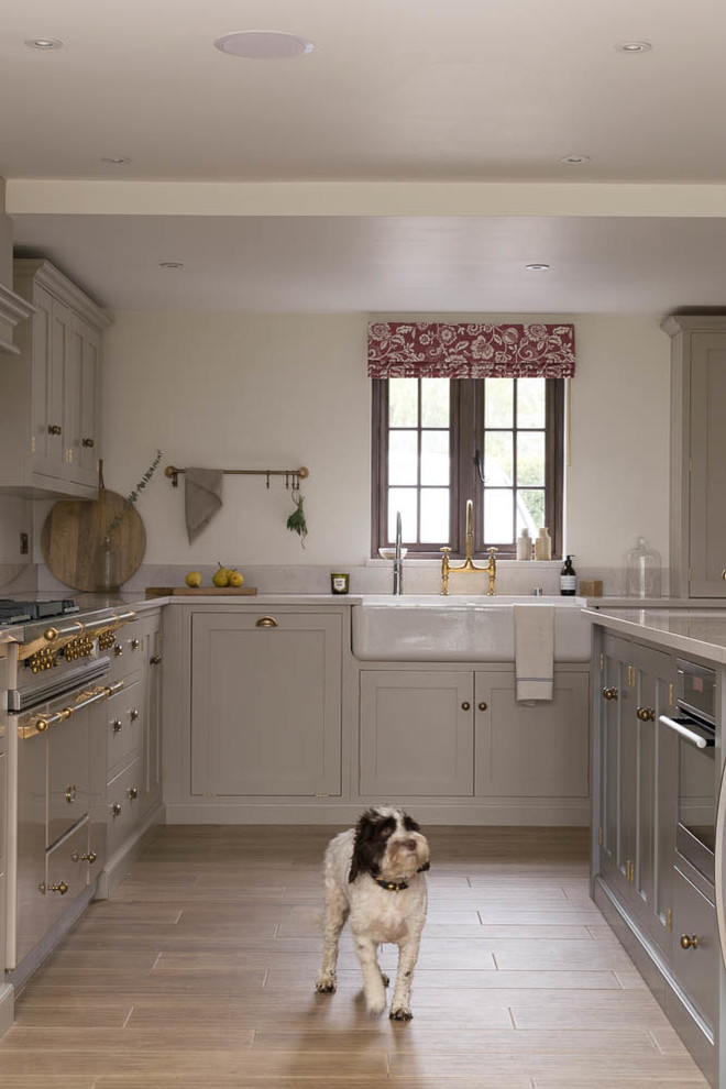 Expansive country l-shaped eat-in kitchen in Other with a farmhouse sink, shaker cabinets, grey cabinets, quartzite benchtops, white splashback, coloured appliances, porcelain floors, with island and brown floor.