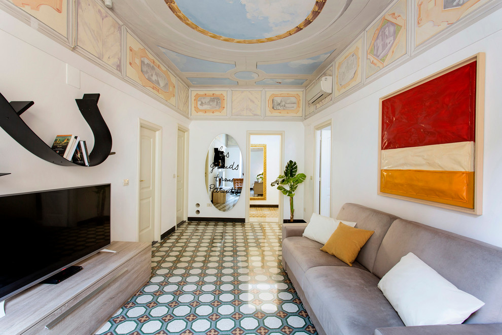 This is an example of a mid-sized mediterranean open concept family room in Florence with a library, white walls, ceramic floors, a freestanding tv and multi-coloured floor.