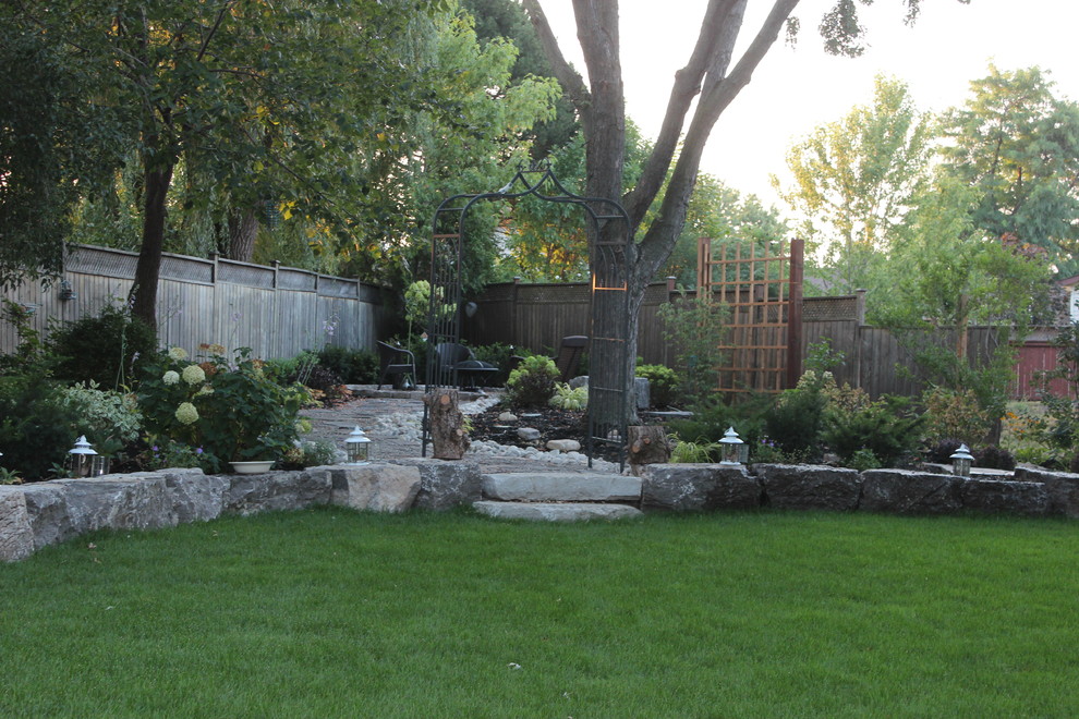 This is an example of a large traditional backyard shaded garden in Toronto with a garden path and natural stone pavers.