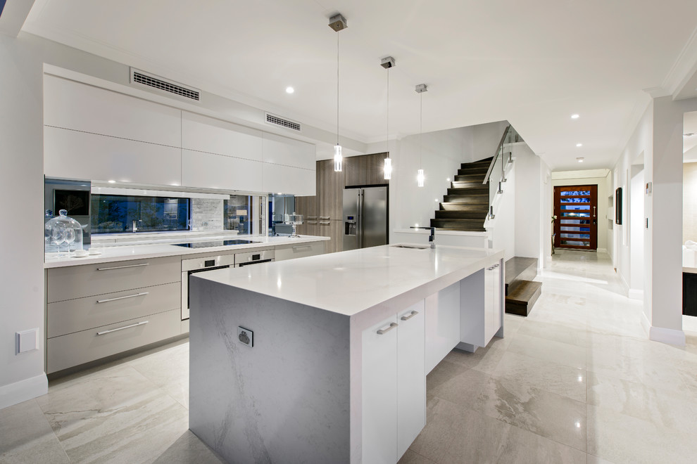 Photo of a contemporary l-shaped kitchen in Perth with an undermount sink, flat-panel cabinets, white cabinets, stainless steel appliances, with island, beige floor and grey benchtop.