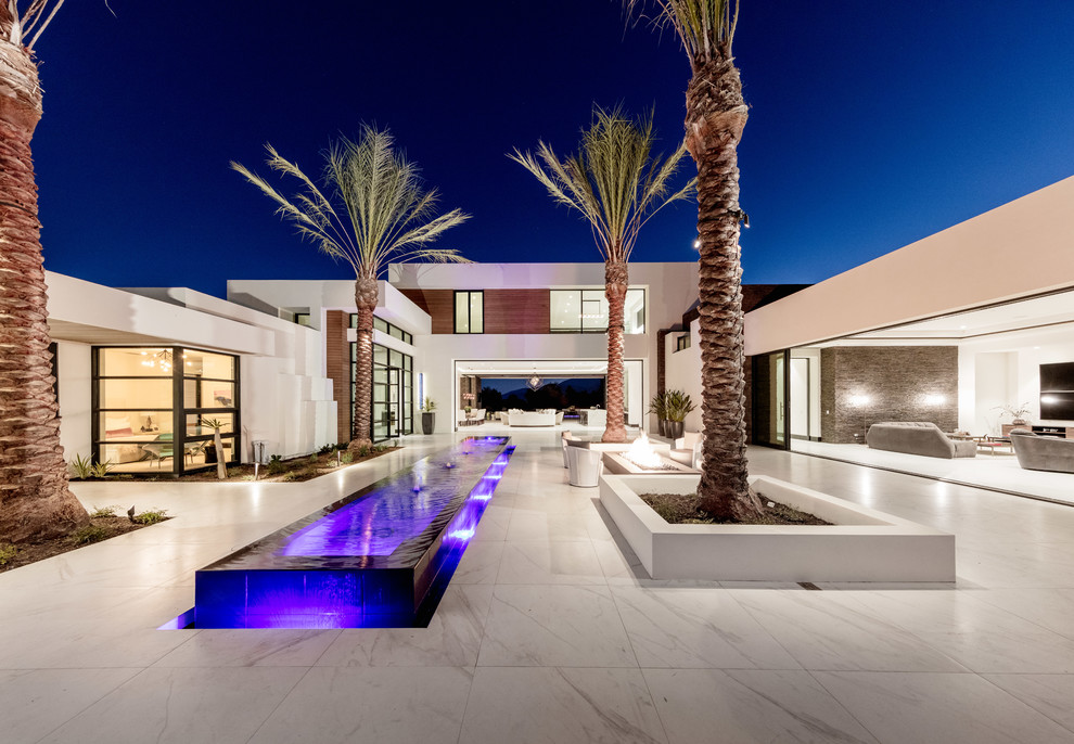This is an example of a contemporary courtyard patio in Orange County with a water feature, tile and no cover.