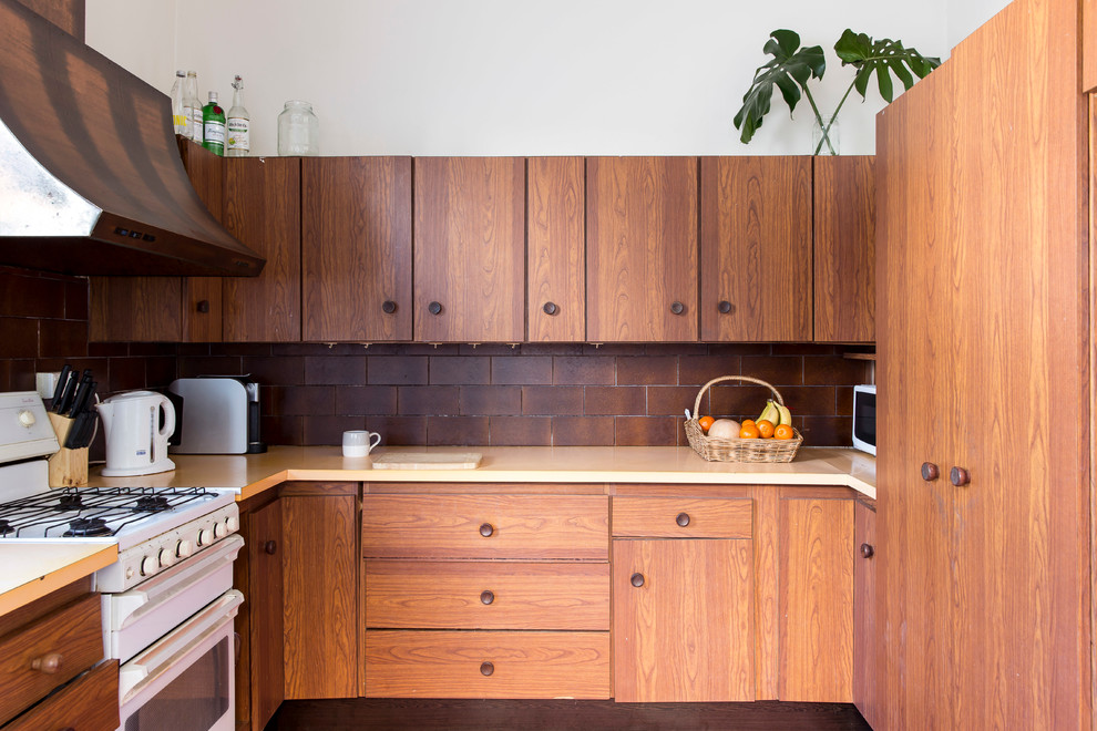 This is an example of a tropical u-shaped kitchen in Sydney with flat-panel cabinets, medium wood cabinets, brown splashback, ceramic splashback, white appliances and no island.