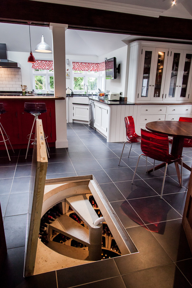 This is an example of a large country open plan kitchen in Hertfordshire with an undermount sink, shaker cabinets, red cabinets, granite benchtops, ceramic splashback, stainless steel appliances, ceramic floors and with island.