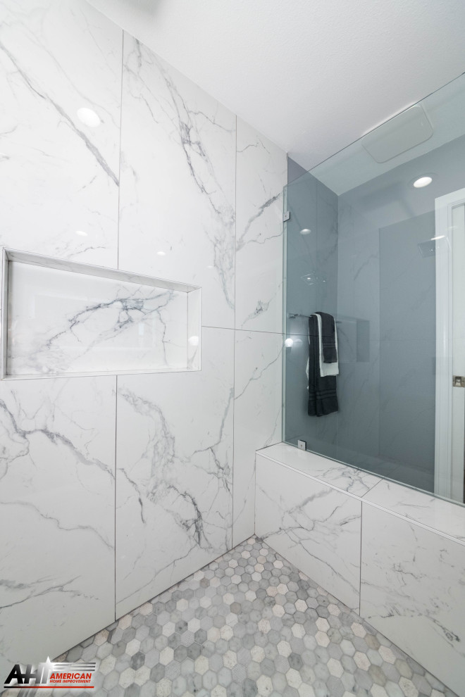 This is an example of a medium sized modern ensuite bathroom in Los Angeles with raised-panel cabinets, white cabinets, a corner shower, a one-piece toilet, white tiles, marble tiles, grey walls, porcelain flooring, a built-in sink, marble worktops, grey floors, a hinged door, white worktops, a shower bench, double sinks and a built in vanity unit.
