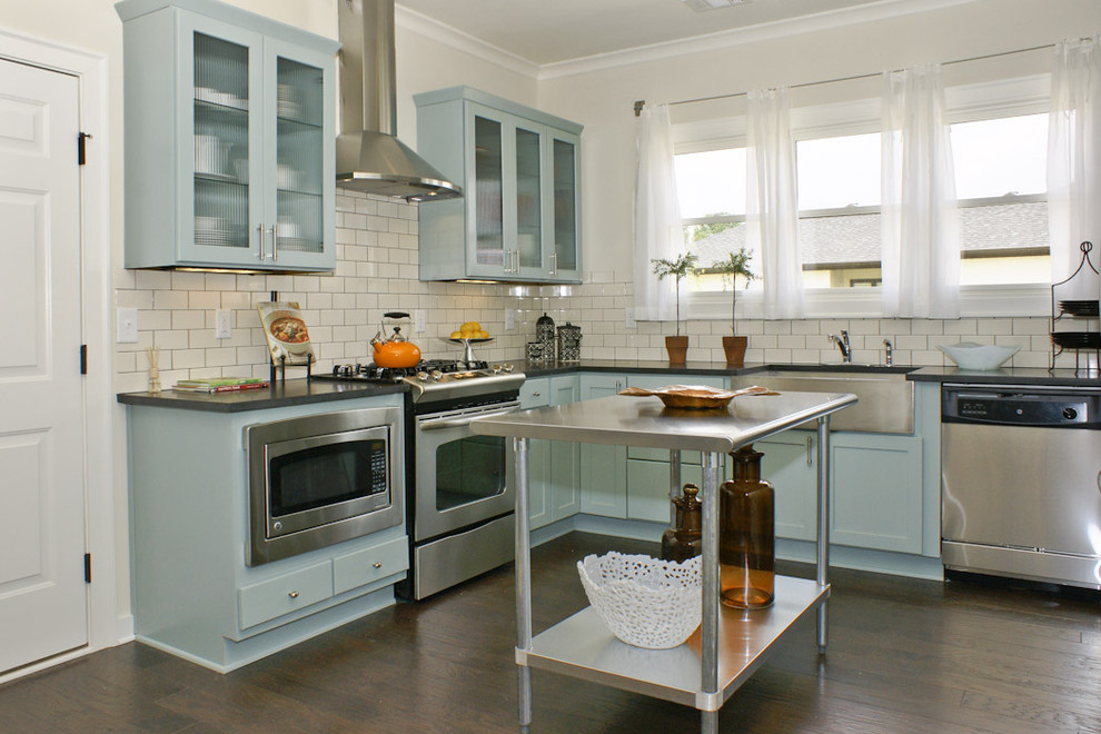 Mid-sized country l-shaped eat-in kitchen in Birmingham with stainless steel appliances, a farmhouse sink, shaker cabinets, blue cabinets, solid surface benchtops, white splashback, subway tile splashback, dark hardwood floors and with island.
