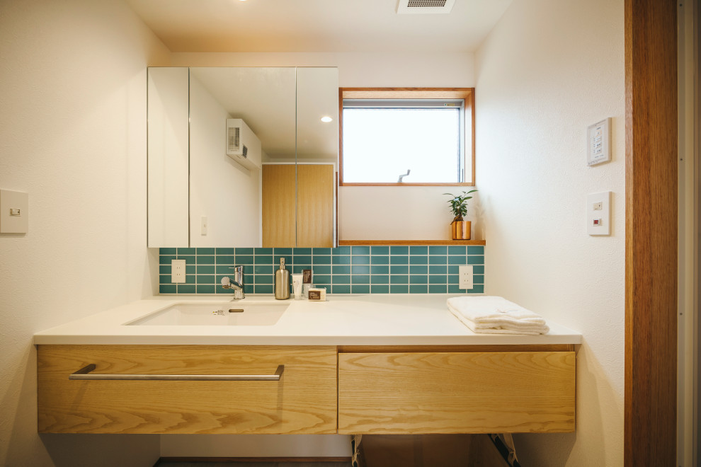 Midcentury powder room in Other with flat-panel cabinets, white cabinets, green tile, subway tile, white walls, medium hardwood floors, solid surface benchtops, white benchtops, a built-in vanity, wallpaper and wallpaper.